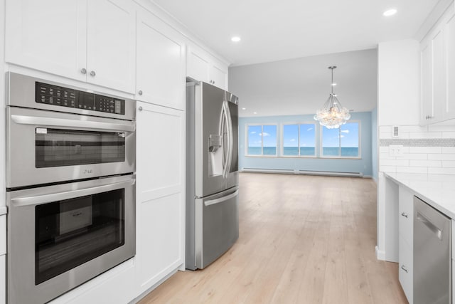 kitchen featuring hanging light fixtures, white cabinets, light stone counters, light hardwood / wood-style floors, and stainless steel appliances