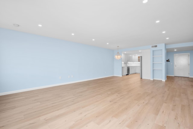 unfurnished living room with a chandelier and light hardwood / wood-style floors