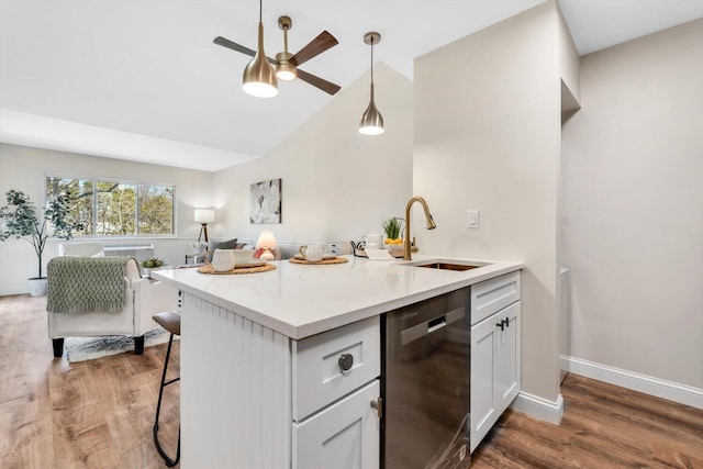 82 Fletcher Ln Unit D, Brewster, MA 02631 - kitchen with stainless steel dishwasher, ceiling fan, a sink, wood finished floors, and a breakfast bar