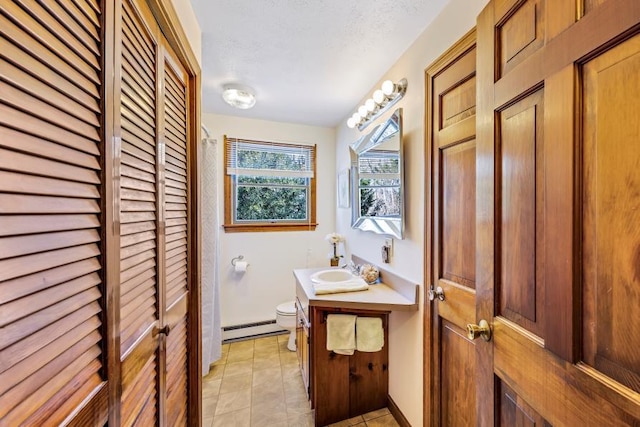 bathroom with toilet, baseboard heating, a closet, vanity, and tile patterned flooring