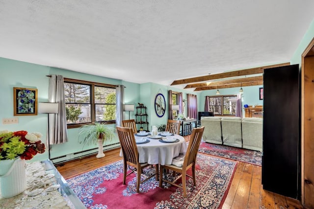 dining area featuring a baseboard heating unit, wood-type flooring, a textured ceiling, and beam ceiling