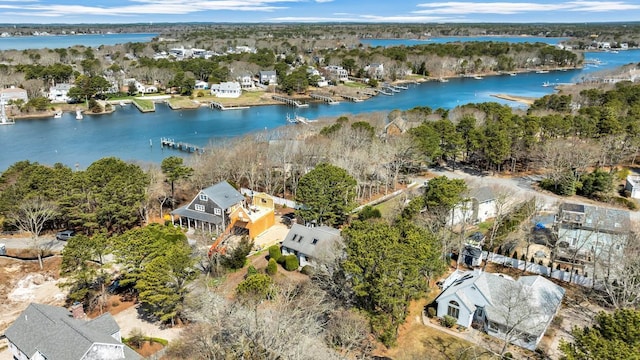 aerial view of property and surrounding area featuring a large body of water, nearby suburban area, and a tree filled landscape