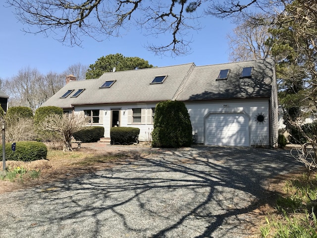 view of front of house featuring dirt driveway, a chimney, an attached garage, and a shingled roof