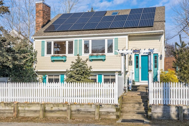 view of front of house with a fenced front yard, a chimney, and roof with shingles