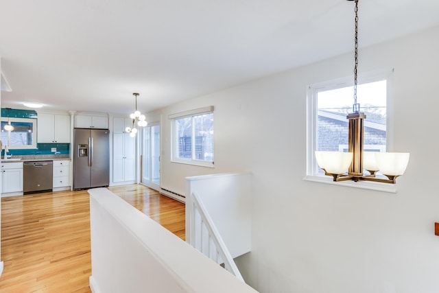 interior space with a chandelier, plenty of natural light, appliances with stainless steel finishes, and a baseboard radiator