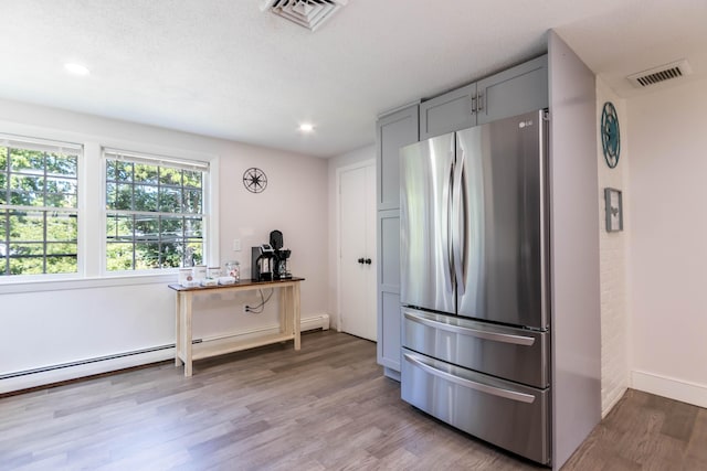 kitchen featuring baseboard heating, stainless steel fridge, gray cabinets, a textured ceiling, and light hardwood / wood-style floors