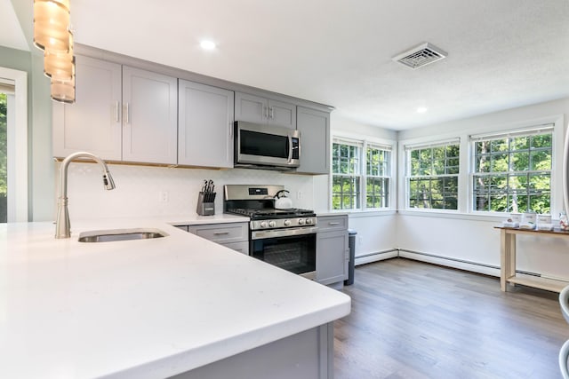 kitchen featuring sink, backsplash, dark wood-type flooring, gray cabinets, and stainless steel appliances