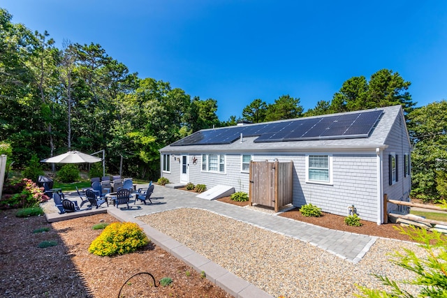 rear view of house featuring a patio area and solar panels