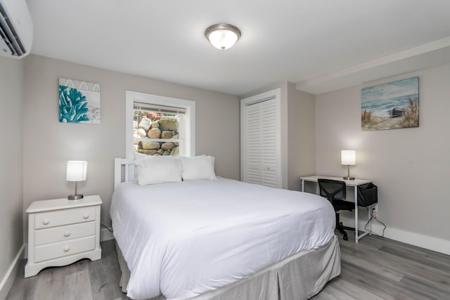 bedroom featuring a closet, an AC wall unit, and wood-type flooring