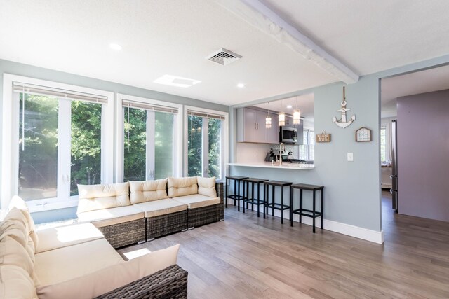 living room with light wood-type flooring, beamed ceiling, and a notable chandelier