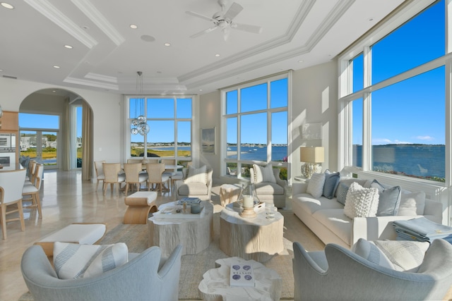 living room featuring a healthy amount of sunlight, a water view, and a tray ceiling