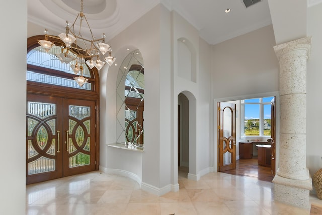 foyer entrance with crown molding, an inviting chandelier, a towering ceiling, and french doors