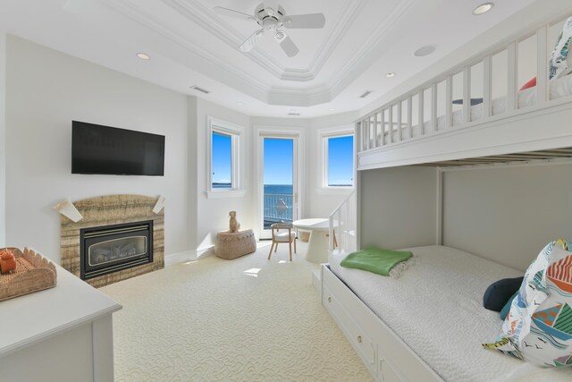 carpeted bedroom featuring ceiling fan, crown molding, and a raised ceiling