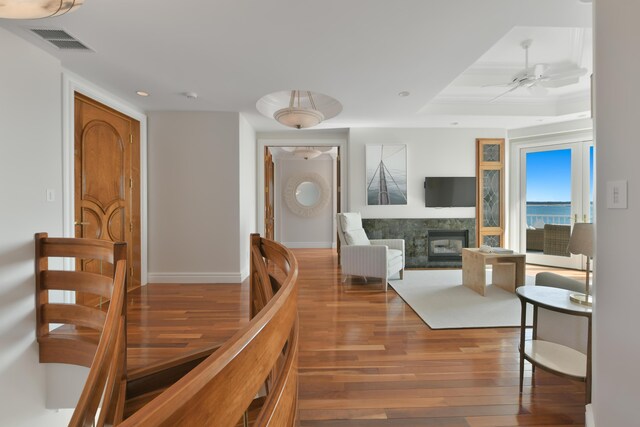 interior space featuring ceiling fan, hardwood / wood-style flooring, a tray ceiling, and a high end fireplace