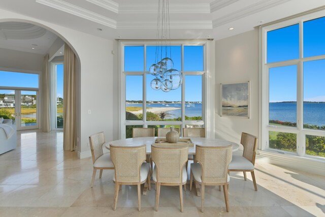 dining space with a healthy amount of sunlight, a water view, and a notable chandelier