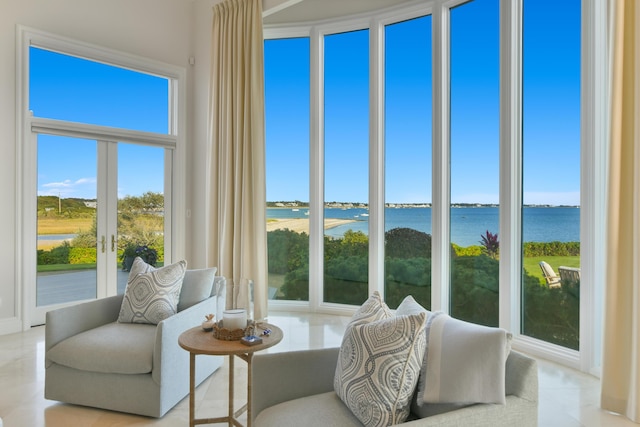 sunroom with a healthy amount of sunlight, a water view, and french doors