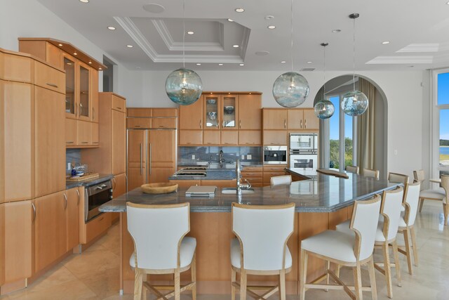 kitchen with built in appliances, decorative light fixtures, a raised ceiling, and a large island