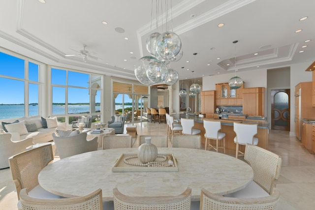 dining room with ceiling fan, ornamental molding, a raised ceiling, and a water view