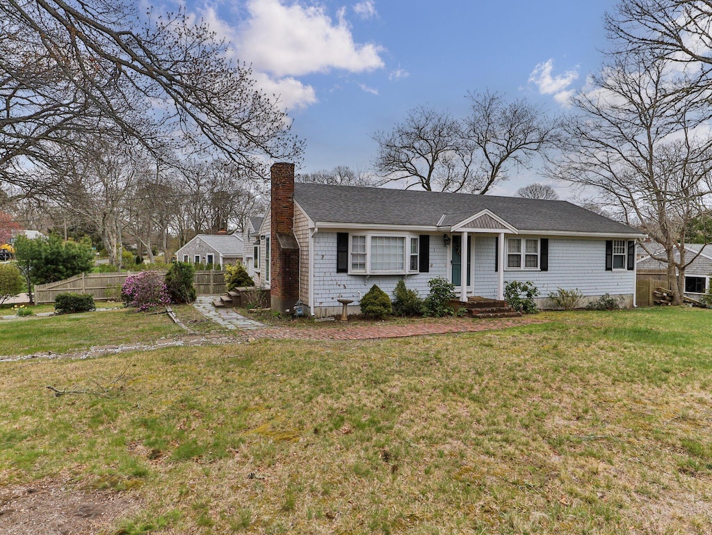 single story home featuring a chimney, fence, roof with shingles, and a front yard