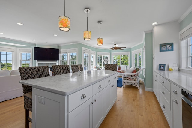 kitchen with white cabinetry, light stone countertops, hanging light fixtures, and a breakfast bar area