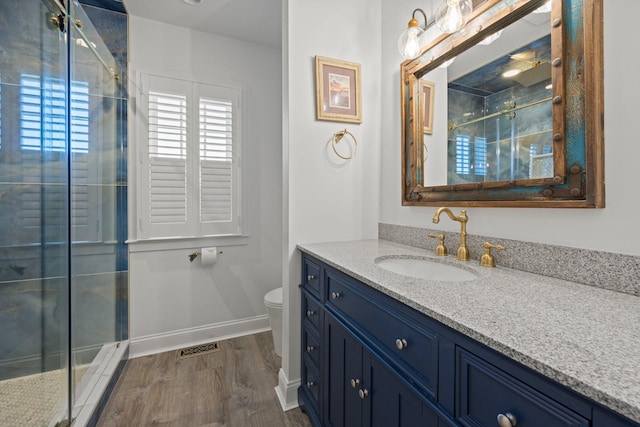 bathroom with hardwood / wood-style floors, walk in shower, vanity, and toilet