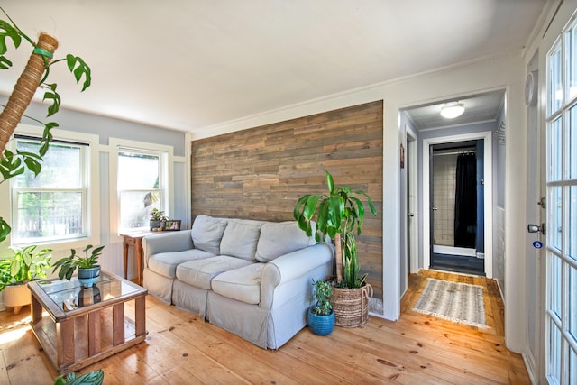 living room featuring wood walls, crown molding, and light hardwood / wood-style floors