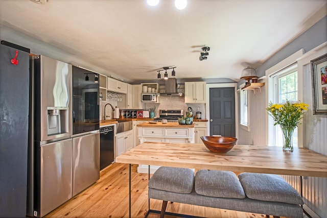 kitchen featuring light hardwood / wood-style floors, tasteful backsplash, wooden counters, sink, and stainless steel appliances