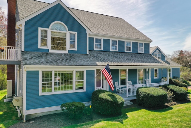 view of front of home featuring a porch, a front lawn, a shingled roof, and a chimney