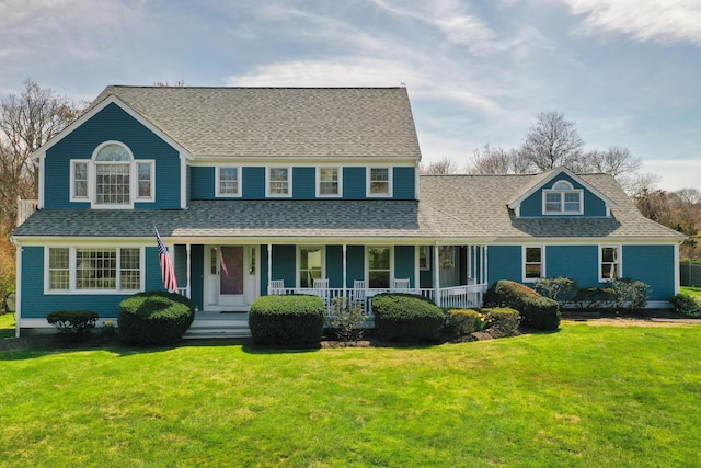 view of front of house featuring covered porch, a front lawn, and roof with shingles