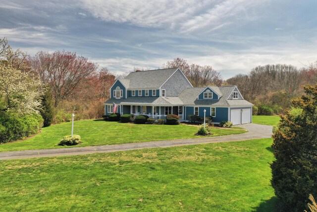 view of front of property with a porch, a front yard, driveway, and an attached garage