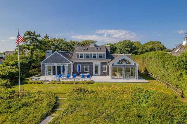 rear view of house with fence, a lawn, and a patio