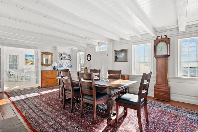 dining area with wood finished floors and beamed ceiling