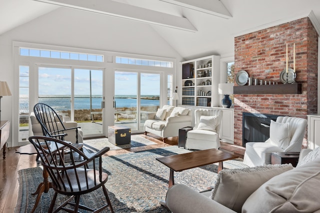 living area with high vaulted ceiling, hardwood / wood-style flooring, a water view, a fireplace, and beamed ceiling