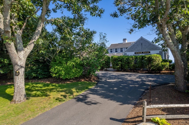 shingle-style home with a front yard, driveway, and a chimney