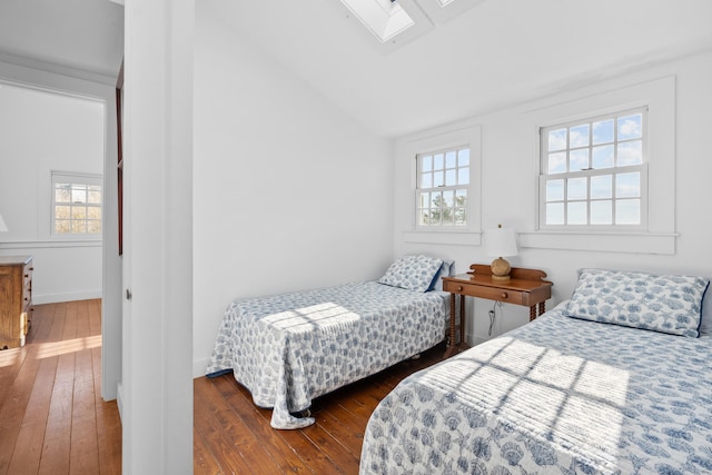 bedroom featuring vaulted ceiling with skylight, baseboards, and hardwood / wood-style floors