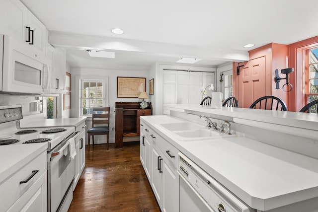 kitchen featuring light countertops, dark wood-type flooring, white cabinetry, a sink, and white appliances