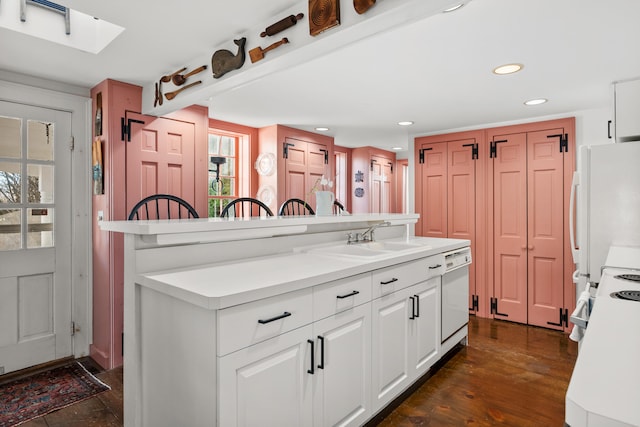 kitchen featuring white appliances, light countertops, a sink, and dark wood-style flooring