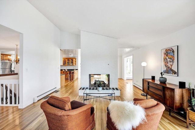 living room with a brick fireplace, light wood-type flooring, a chandelier, and baseboard heating