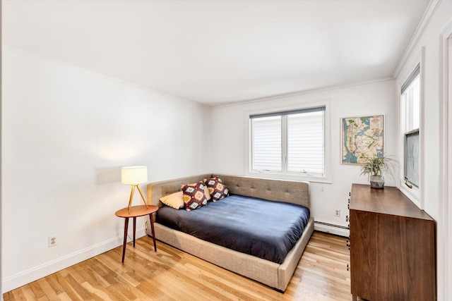 bedroom featuring a baseboard heating unit, crown molding, and hardwood / wood-style floors