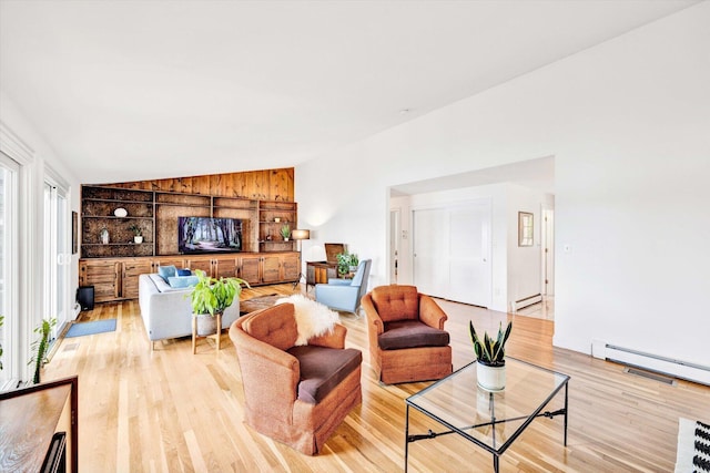 living room with lofted ceiling, light hardwood / wood-style floors, and a baseboard heating unit