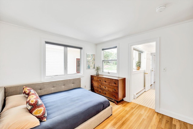 bedroom featuring crown molding, a baseboard radiator, and light wood-type flooring