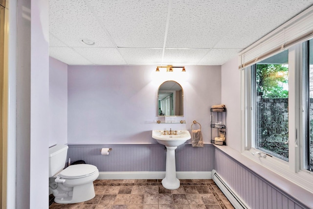 bathroom featuring a paneled ceiling, toilet, and a baseboard heating unit