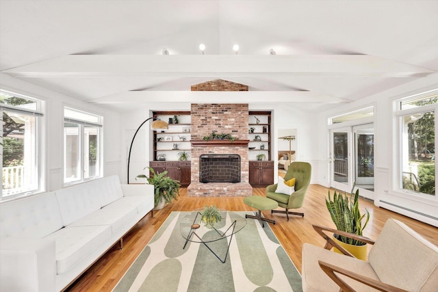 interior space featuring built in shelves, lofted ceiling with beams, light wood-type flooring, a baseboard radiator, and a fireplace