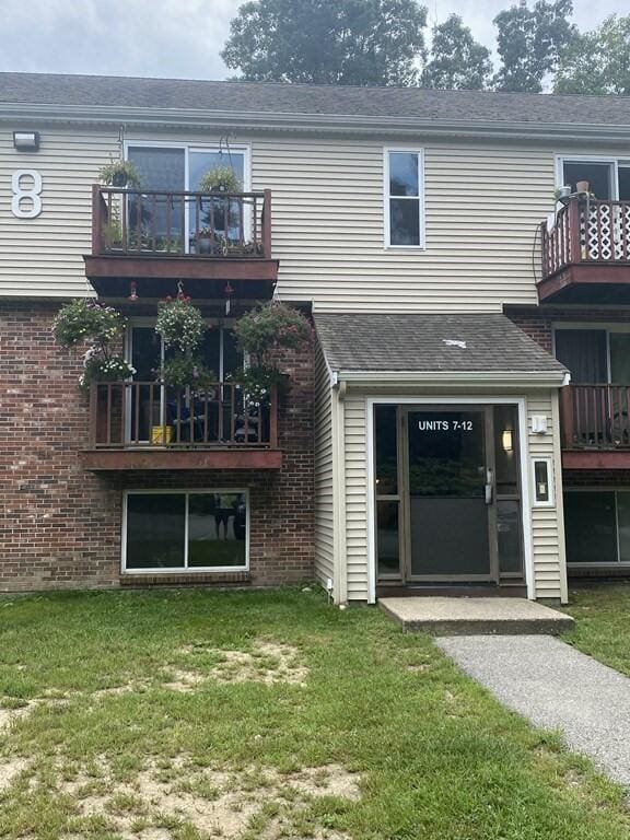 back of house with a balcony and a yard