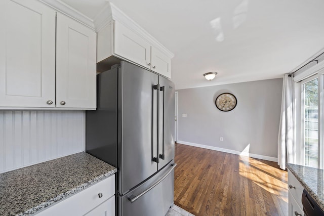 kitchen featuring dark wood-style flooring, light stone countertops, high end refrigerator, baseboards, and white cabinetry