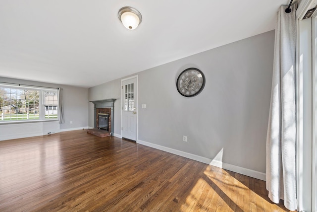 unfurnished living room featuring baseboards, wood finished floors, and a fireplace
