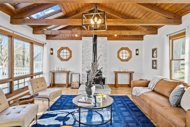 living area featuring wooden ceiling, lofted ceiling with skylight, wood finished floors, a wood stove, and an inviting chandelier