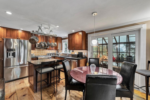 dining space featuring sink, light hardwood / wood-style flooring, and ornamental molding