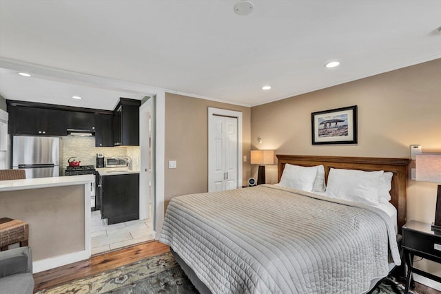 bedroom with sink, stainless steel refrigerator, ornamental molding, and wood-type flooring