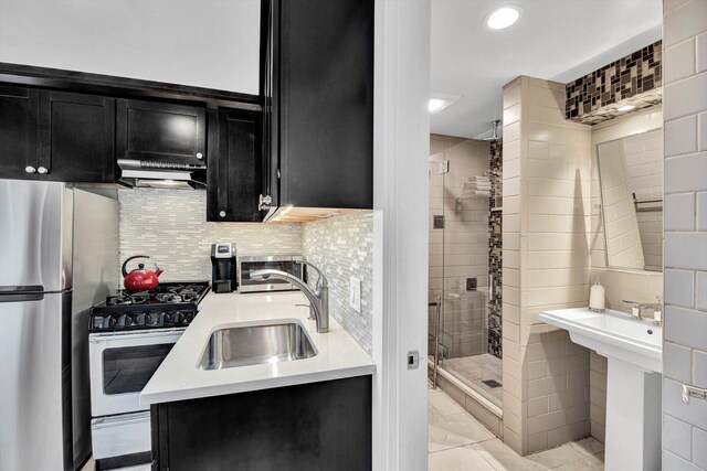 kitchen featuring appliances with stainless steel finishes, sink, light tile patterned flooring, ventilation hood, and decorative backsplash